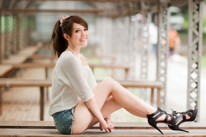Asian woman with long hair wearing a sweater and jean shorts