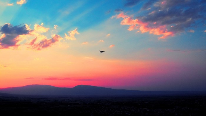 Airplane flying over mountains at sunset