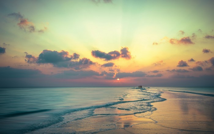 Beach sunset over the sea with two people