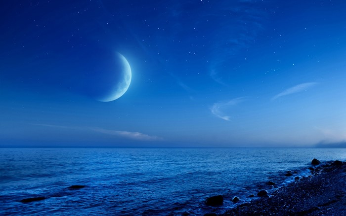 Crescent moon over the ocean at night