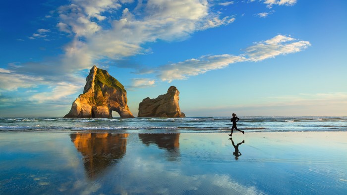 Serene Beach with Rock Formation and Runner