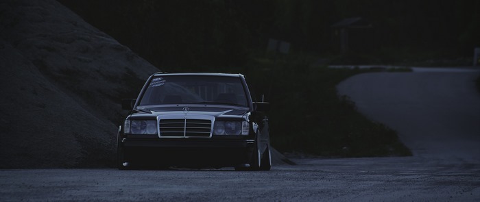 Black Mercedes-Benz W124 parked on gravel road