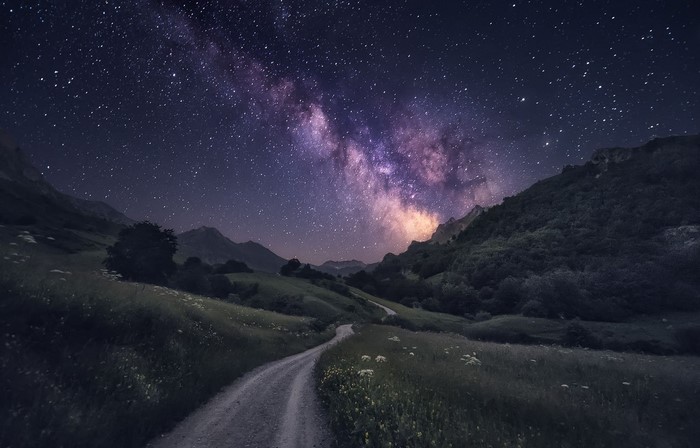Milky Way over a mountain valley with a dirt road
