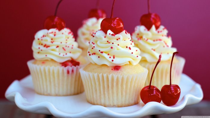 Cupcakes with cherries and sprinkles on a cake stand