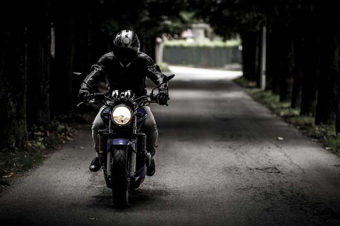 Motorcyclist on a dark tree-lined road