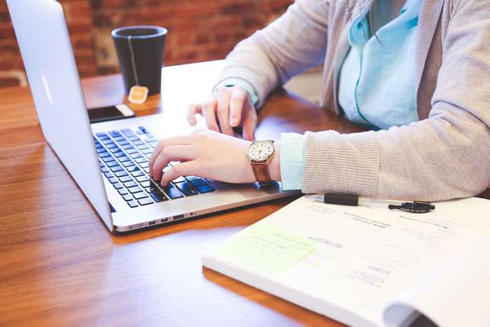 Woman working on a MacBook Pro with a notebook