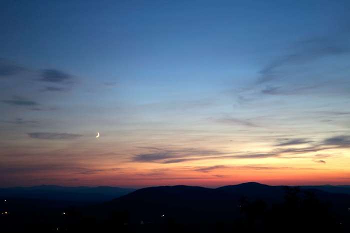 Crescent moon in the twilight sky over mountains