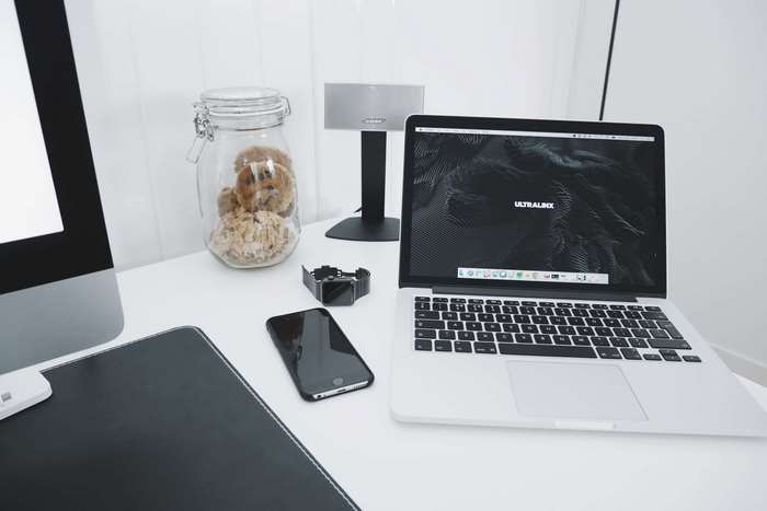 MacBook, iPhone, and jar of cookies on a desk