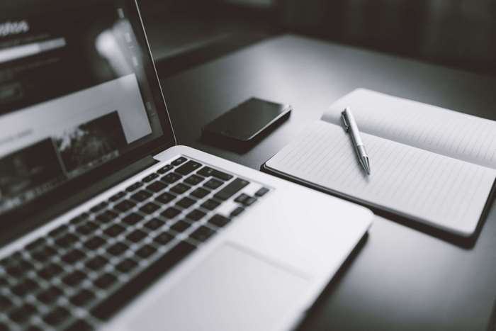 Laptop, smartphone, and notebook with pen on desk