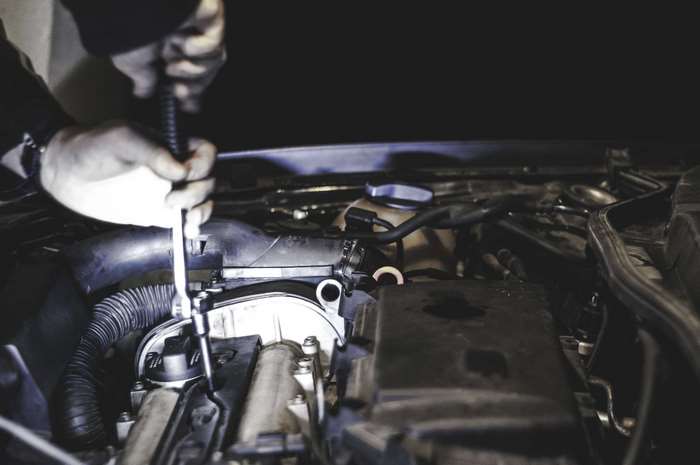 Mechanic fixing a car engine with a wrench