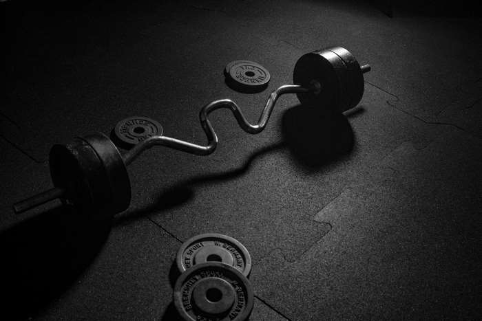 Curved barbell with weight plates on gym floor