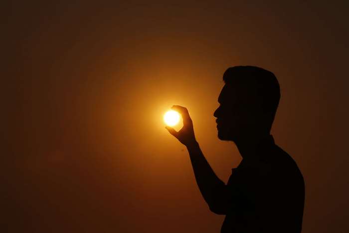 Man holding the sun at sunset