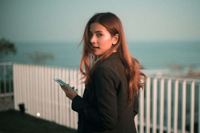 Woman in a suit holding a smartphone outdoors