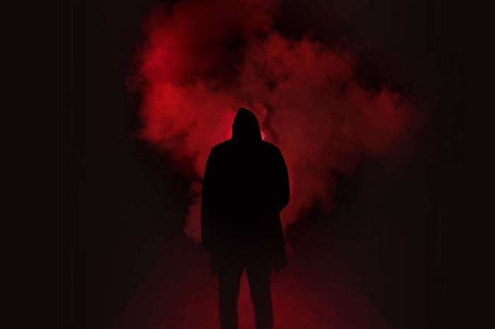 Silhouette of Man in Red Smoke with Dark Background
