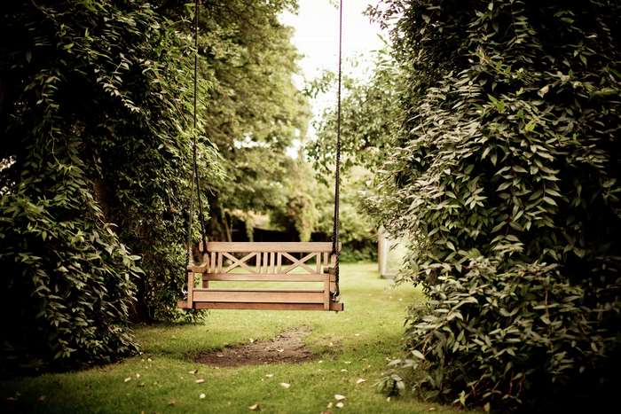 Wooden swing in a garden with trees and grass 4K