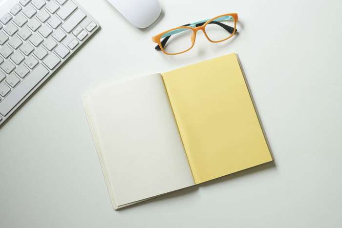 Open notebook, glasses, keyboard, and mouse on a desk
