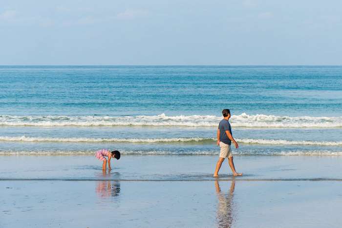 Father and child walking on a beach by the ocean