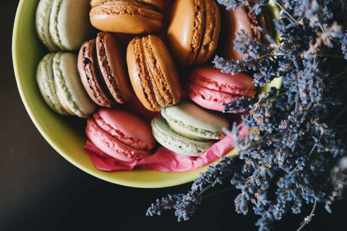 Assortment of colorful macarons in a bowl with lavender