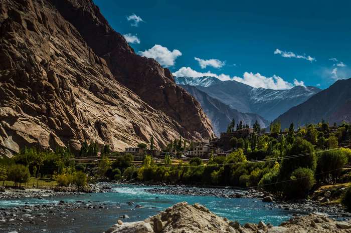 River flowing through Ladakh mountains with village and snow-capped peaks