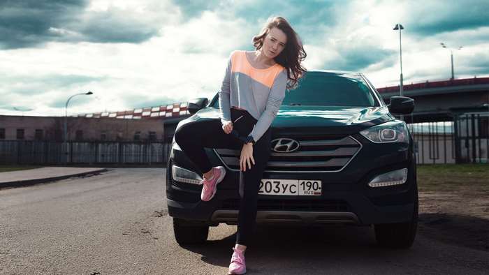 Woman posing with Hyundai SUV on a cloudy day