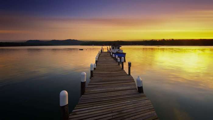 Wooden dock with boat at sunset on a calm lake