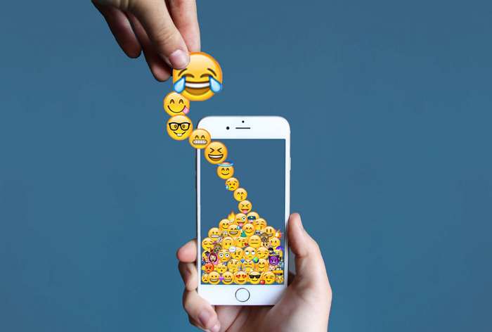 Hand dropping emojis onto iPhone screen