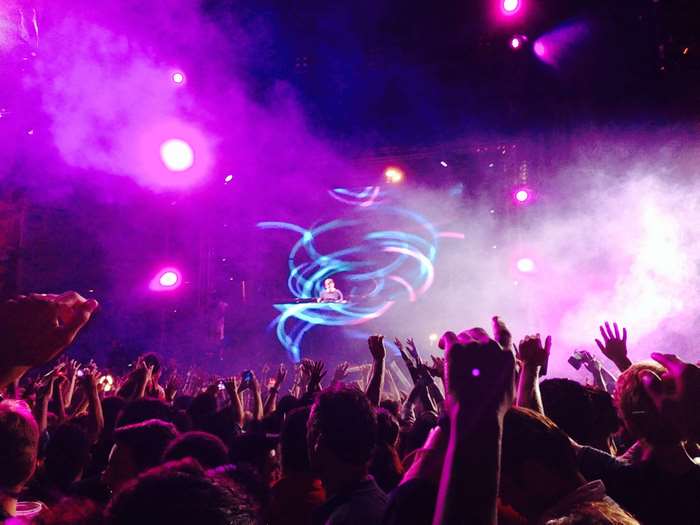 DJ performing for a crowd at a concert with purple lights