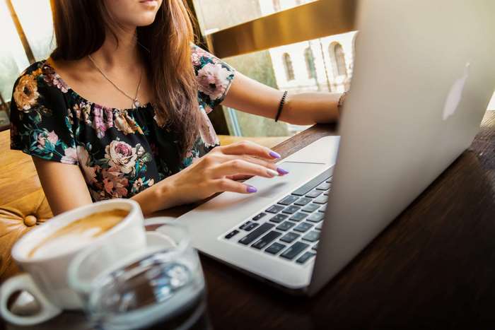 Woman working on Apple laptop with coffee