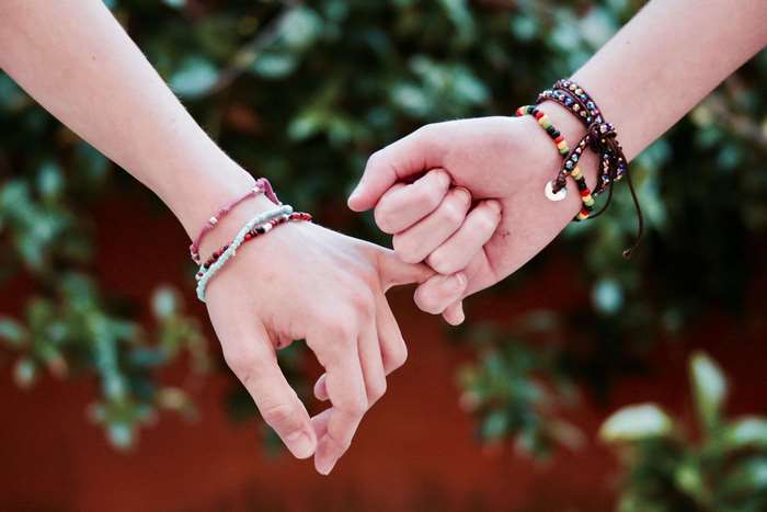 Two hands pinky promising with bracelets