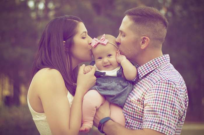 Parents kissing their baby girl