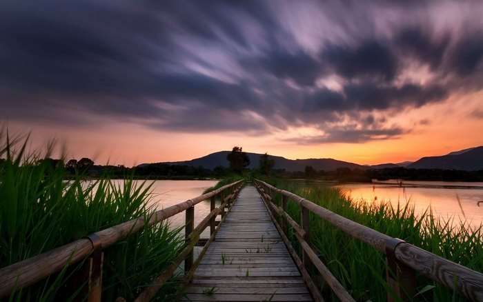 Wooden pier over a lake at sunset with clouds
