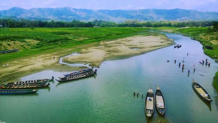Boats on a river with green fields and mountains