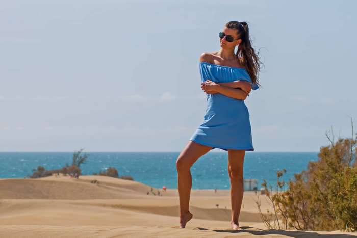 Woman in blue dress on sand dunes by the sea