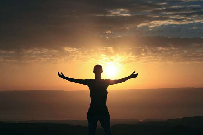 Silhouette of a person with arms outstretched at sunset