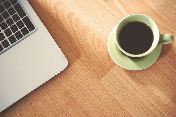 Laptop and coffee cup on a wooden table