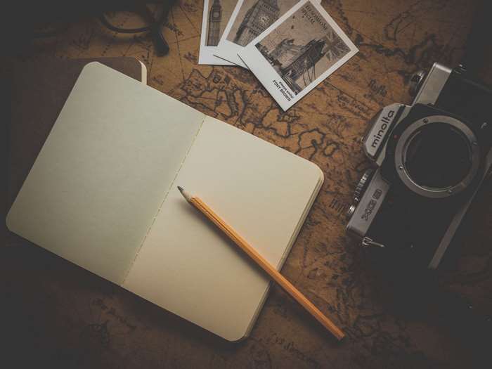 Vintage travel items: notebook, pencil, camera, photos, and map