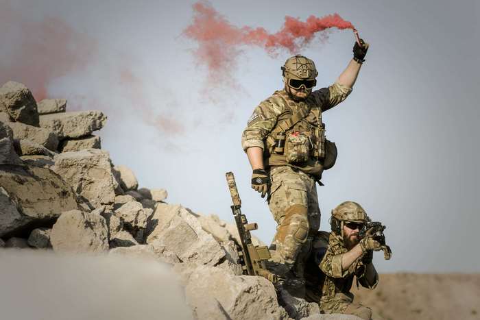 Soldiers with smoke grenade and rifle in desert