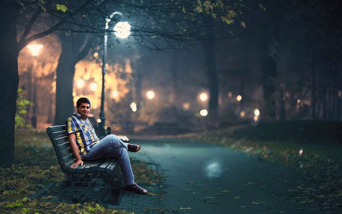Man sitting on a park bench at night
