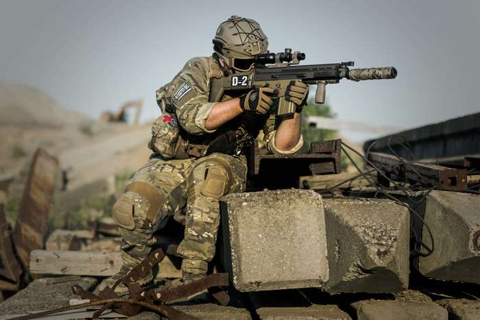 Soldier in camouflage aiming a rifle