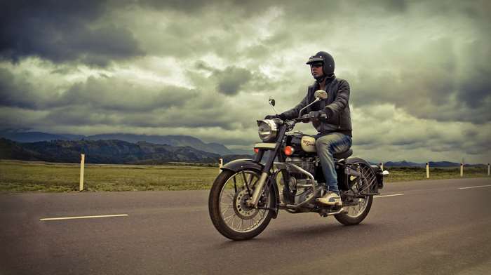 Man riding a Royal Enfield motorcycle on a road