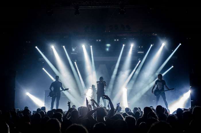 Band performing on stage with spotlights and crowd