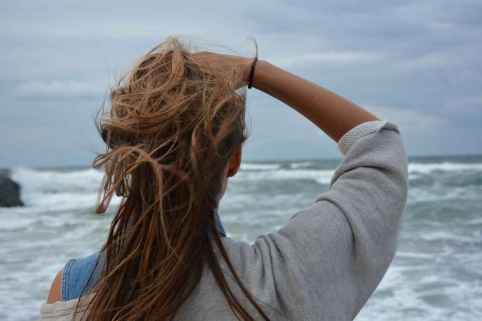 Young woman looking at the ocean on a windy day