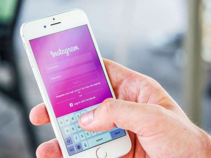 Person holding an iPhone displaying the Instagram login screen