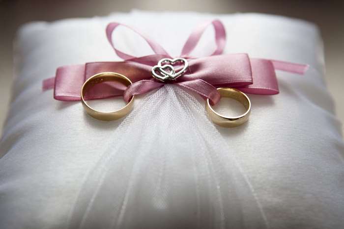 Wedding rings on a pillow with a pink ribbon
