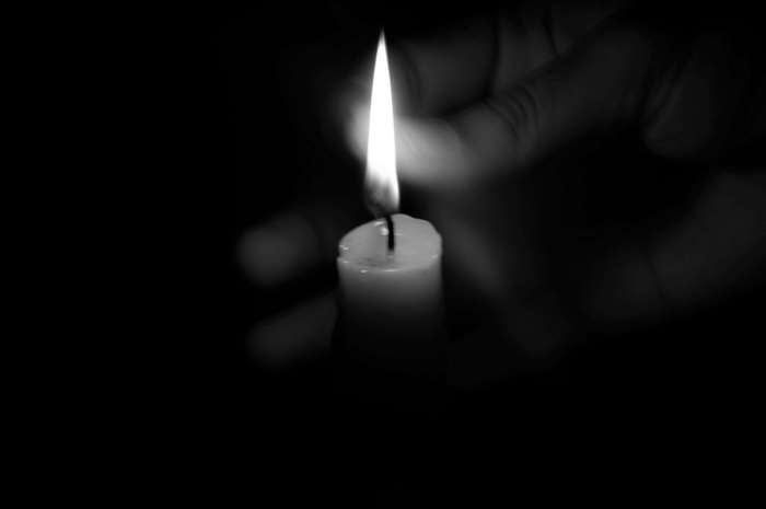 Hand holding a lit candle in the dark