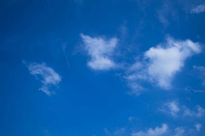 Blue sky with white clouds and a contrail
