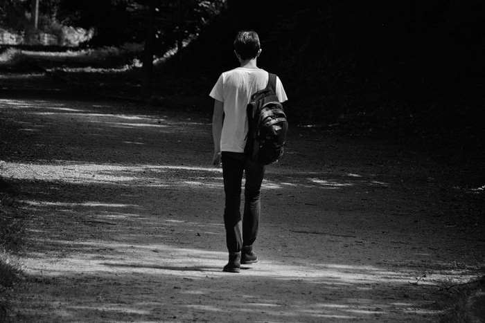 Young man with backpack walking on a path