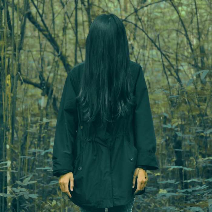 Woman with long black hair in a dark forest