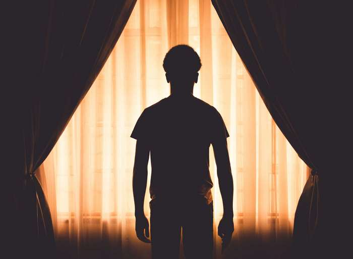 Silhouette of a person standing in front of a window