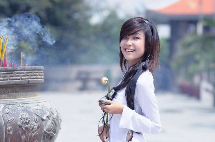 Young Asian woman in traditional white dress with incense smoke